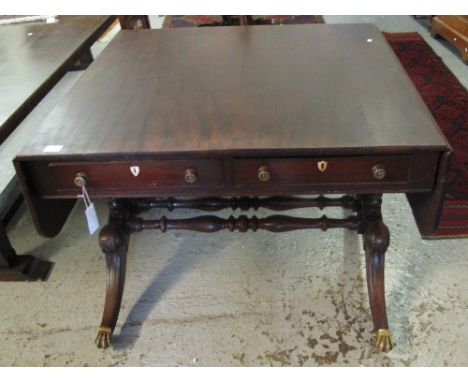 Early 19th Century mahogany sofa table on scrolled outswept legs with brass paw cups and casters.