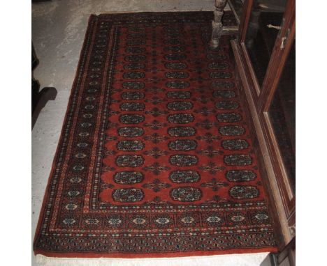Middle Eastern design geometric carpet on a rust coloured ground with central gul panels.