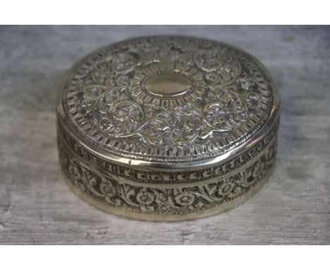 White metal oval trinket pot with cover, repousse floral and foliate scroll decoration to the cover and body, blank cartouche