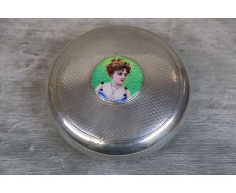 Early 20th century silver circular tobacco pot with raised enamel plaque to centre depicting a lady's profile, engine turned 