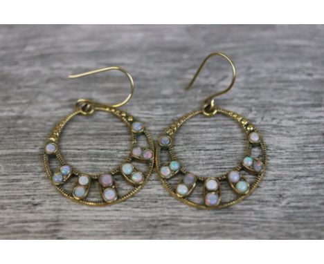 Pair of opal 9ct yellow gold drop earrings, the pierced circular design set with twelve small round cabochon cut precious whi