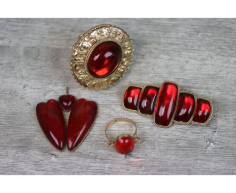 Red amber type yellow metal ring, the central stone with rope twist border and repousse foliate decoration to broad yellow me