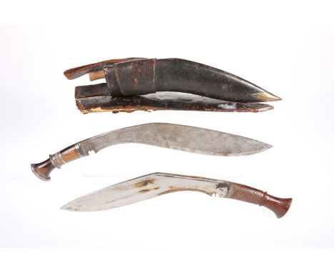 A KUKRI, with steel blade, carved wood handle, brass hilt and bass mounted leather scabbard, with smaller blade, blade 33cm l