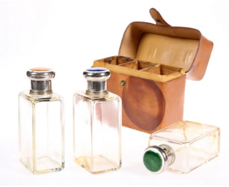 A SET OF THREE CASED CUT GLASS BOTTLES, rectangular form, each with a twist off silver-plated lid and decorated in green, ora