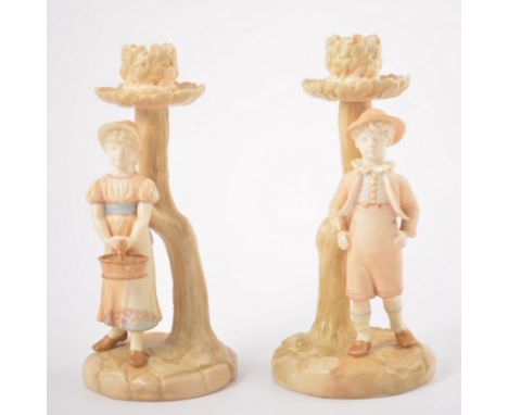 Royal Worcester ivory ground candlesticks, designed with a boy and a girl by a tree, printed and impressed marks, 19cm.
