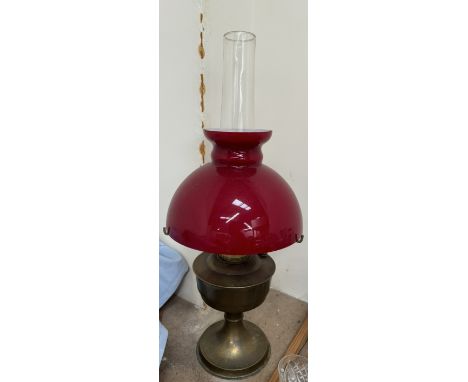 A brass oil lamp with a red glass shade 