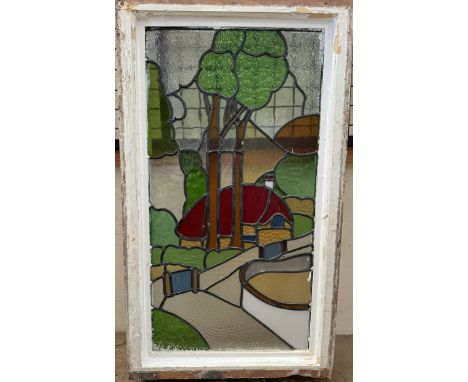 A stained glass window depicting a cottage in a landscape, 85 x 44cm (panel size) the image is reminiscent of a Clarice Cliff