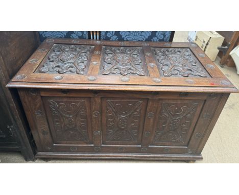 A carved oak trunk with a three panelled carved top and front on stiles 106cm wide x 55.5cm deep x 63.5cm high