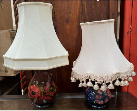A Moorcroft pottery table lamp with a red ground and tube lined flowers and leaves together with another Moorcroft table lamp