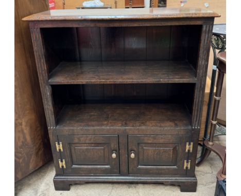 An 18th century style oak bookcase with a rectangular top and shelf above a pair of cupboard doors on bracket feet