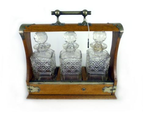 An early 20th century oak and white metal mounted tantalus containing three cut glass decanters. h. 33 cm, w. 36 cm, d. 13.5 