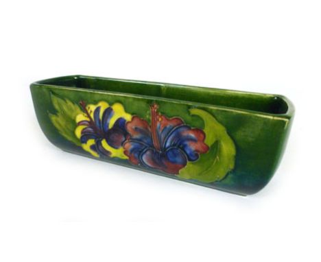 A Moorcroft trough vase decorated with a Hibiscus pattern on green ground, with a paper Moorcroft label to the base l. 20cm