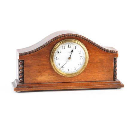 OAK CASED MANTLE CLOCK WITH A CIRCULAR PORCELAIN DIAL & FRENCH MOVEMENT.  RETAILER: FRED J. MALCOLM LTD BELFAST.HEIGHT: 6 INC