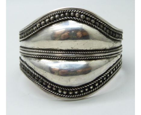 A handmade white metal statement bangle, possibly South American, indistinctly stamped 925, 40g