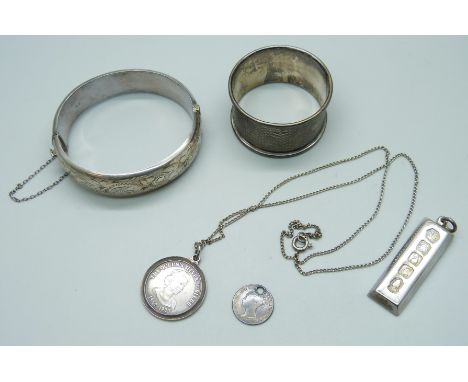 A collection of silver - a bangle, ingot, drilled coin, pendant on a white metal chain, and a napkin ring, 73.9g