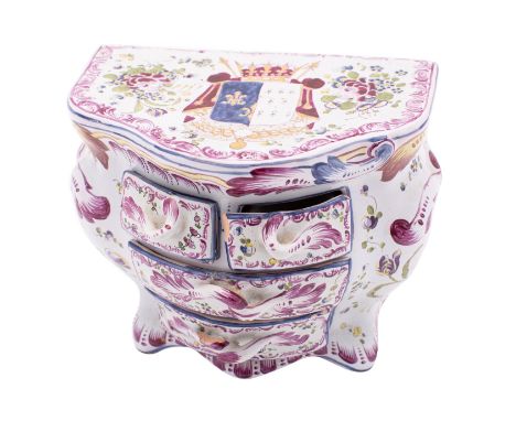 A French faience model of a miniature bombe commode of four drawers, painted with flowers and foliage and an elaborate coat-o