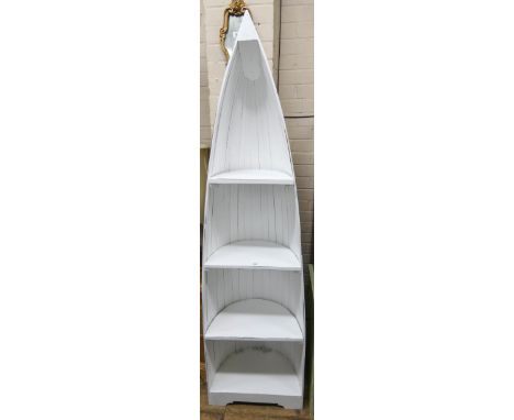 A tall white painted boat shaped reclaimed bookcase or display shelf 