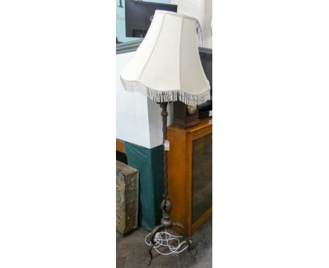 An Art Nouveau bronze standard lamp with adjustable column, possibly later converted to electricity with a fringed shade  