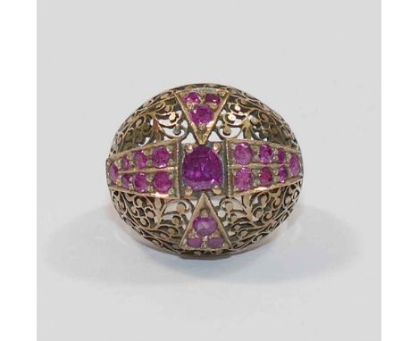 A ruby set bombè shaped ring, the central oval mixed cut ruby set within a cross arrangement of smaller round rubies, within 