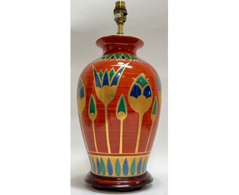 A brightly glazed Egyptian style ceramic lamp base with Mediterranean floral decoration and gilt, raised on a wooden base (to