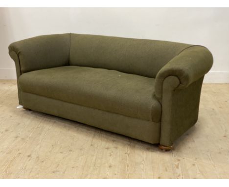 An early 20th century Chesterfield sofa, upholstered in green, and raised on compressed bun supports with recessed castors. H