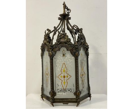 An early 20th century cast and repousse brass hall lantern of octagonal outline, inset with etched and coloured glass panels 