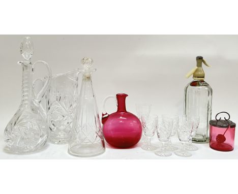 A mixed group of glassware comprising two crystal decanters (largest h- 36cm), a cranberry glass pitcher (no stopper), a cran