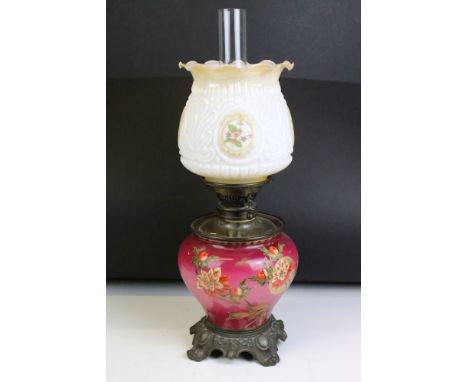 An antique oil lamp having floral decoration to base and opaque shade and scrolled feet. Measures approx 54cm high 
