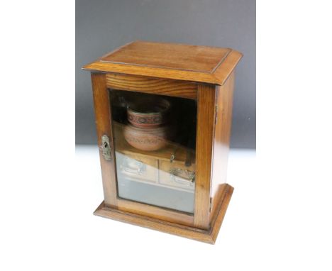 Edwardian oak smokers cabinet, the glazed door opening to two drawers, and upper and lower storage compartments, the upper co