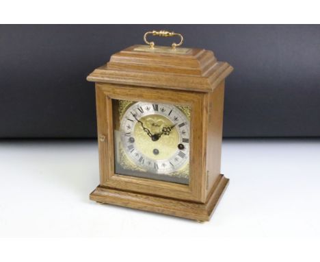 Oak cased Woodford bracket clock, the brass dial with silvered chapter ring, glazed front door, brass carry handle. Measures 