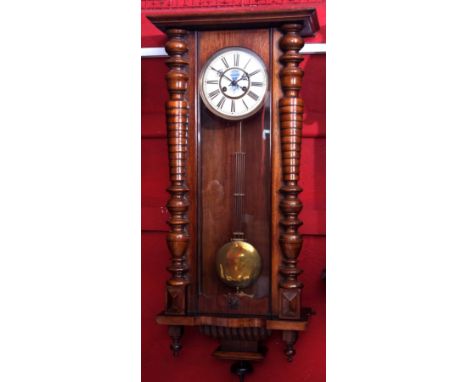 Early 20th century walnut cased Vienna type wall clock with overhanging cornice and baluster turned half columns to a shaped 