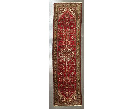 An early 20th century Persian Islamic Bijar floor carpet runner rug. The runner having a red ground central panel with floral