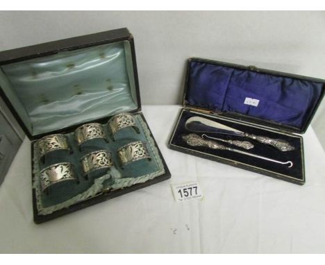 A cased set of 6 silver napkin rings and a cased shoehorn and button hook set.