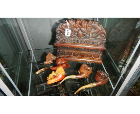 An ornately carved wood pipe rack with 5 pipes including horse heads.