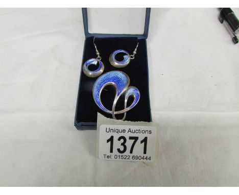 A pair of enamel ear pendants with matching brooch in light and medium blue enamel in the art nouveau style set in silver.
