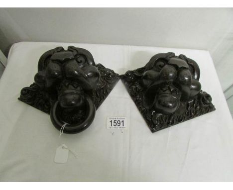 A pair of carved wood lion head wall plaques (one missing ring).