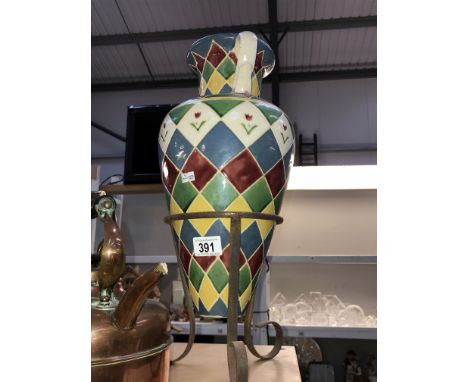 A colourful glazed amphora vase on a metal tripod stand