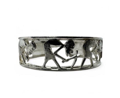 A Makonde open work torc bangle, featuring figures engaged in agricultural work in relief. In white precious metal assessed a