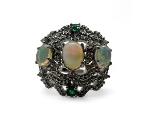 An opal, emerald and diamond set dress ring, in silver. Set with three opal cabochons, to an estimated total weight of 1.80 c