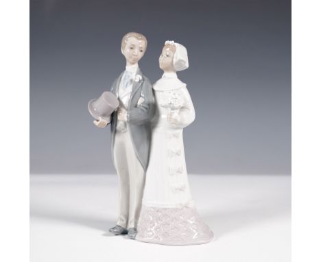 This Lladro porcelain figurine, titled Wedding (model 1004808), portrays a newlywed couple in an elegant embrace. The groom, 