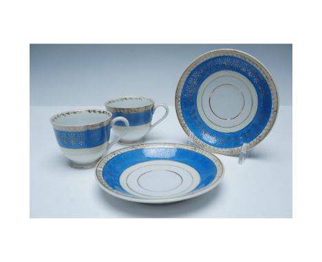 Elegant porcelain cup and saucer sets marked Made in Occupied Japan. Each set features a striking cobalt blue band adorned wi
