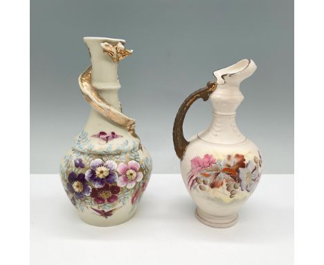 A pair of hand-painted Austrian porcelain ewers, each featuring intricate floral motifs and ornate gilt accents. The first ew