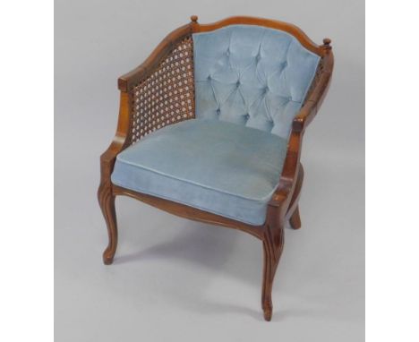 A hardwood Regence style bergere armchair, with blue button back upholstery and over stuffed seat, raised on cabriole legs.