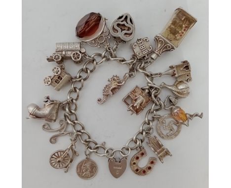 A silver charm bracelet with 18 charms to include stork, bible, boot with mice, gothic chair, man playing piano, horseshoe, p