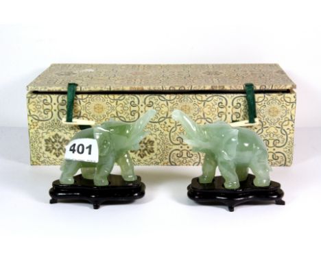 A pair of late 20th century Chinese carved jade figures of elephants on wooden stands, H. 9cm.
