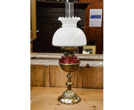 A mid Victorian brass oil lamp, by Hunks, Duplex with a glass funnel, Cranberry glass reservoir pierced brass stand and an op