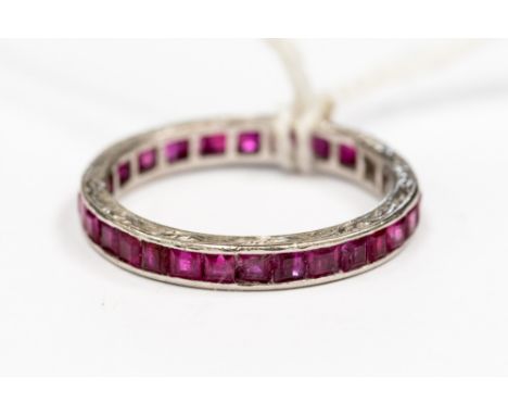 A ruby set platinum full eternity ring, channel set with square cut rubies, the platinum ring has engraved detail on the side