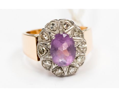 An amethyst and diamond oval cluster ring, in white and rose metal with an oval central amethyst measuring approx 9 x 6mm wit