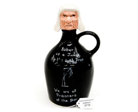 A black drinks decanter with Judges head stopper inscribed 'Sober as a Judge to the last drop, we are all prisoners at the ba