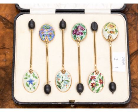 A set of six gilt and enamel coffee spoons, with bean finials, each enamelled a different flower, in case 